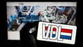 Person holding cellphone with logo of Dutch manufacturing company VDL Groep B.V. on screen in front of business webpage.