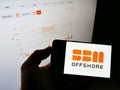 Person holding cellphone with logo of Dutch oil and gas company SBM Offshore on screen in front of website with stock chart.