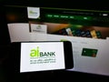 Person holding cellphone with logo of financial company Arab Investment Bank (AIB Egypt) on screen in front of webpage.