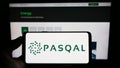 Person holding cellphone with logo of French quantum processing company PASQAL SAS on screen in front of business webpage.