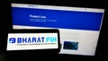 Person holding cellphone with logo of Indian company Bharat FIH Private Ltd on screen with webpage.