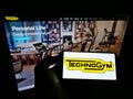 Person holding cellphone with logo of Italian fitness equipment company Technogym SpA on screen in front of business website.