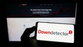Person holding cellphone with logo of online platform Downdetector (Ookla LLC) on screen in front of webpage. Royalty Free Stock Photo