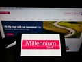 Person holding cellphone with logo of Polish financial company Bank Millennium S.A. on screen in front of business website.