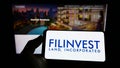 Person holding cellphone with logo of real estate company Filinvest Land Inc. (FLI) on screen in front of webpage.