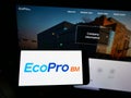Person holding cellphone with logo of South Korean company Ecopro BM Co. Ltd. on screen in front of business webpage.
