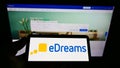 Person holding cellphone with logo of Spanish online travel agency Vacaciones eDreams S. L on screen in front of webpage.