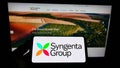 Person holding cellphone with logo of Swiss agriculture company Syngenta Group on screen in front of business webpage. Royalty Free Stock Photo