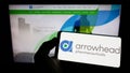Person holding cellphone with logo of US company Arrowhead Pharmaceuticals Inc. on screen in front of business webpage.