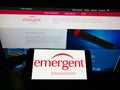 Person holding cellphone with logo of US company Emergent BioSolutions Inc. on screen in front of business website.