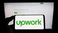 Person holding cellphone with logo of US freelancing platform Upwork Global Inc. on screen in front of company webpage. Royalty Free Stock Photo