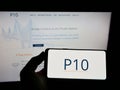 Person holding cellphone with logo of US investment company P10 Holdings Inc. on screen in front of business webpage. Royalty Free Stock Photo