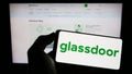 Person holding cellphone with logo of US job review company Glassdoor Inc. on screen in front of business webpage. Royalty Free Stock Photo