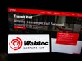 Person holding cellphone with logo of US rail manufacturing Wabtec Corporation on screen in front of business web page.