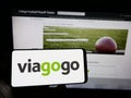 Person holding cellphone with logo of US ticket exchange platform company Viagogo on screen in front of business webpage.
