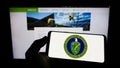 Person holding cellphone with seal of United States Department of Energy (DOE) on screen in front of webpage.