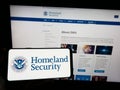 Person holding cellphone with seal of US Department of Homeland Security (DHS) on screen in front of webpage. Royalty Free Stock Photo