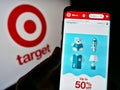 Person holding cellphone with web page of American retail company Target Corporation on screen in front of logo.