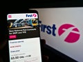 Person holding cellphone with web page of British transport company FirstGroup plc on screen in front of logo.