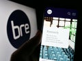 Person holding cellphone with web page of Building Research Establishment (BRE) on screen in front of logo.