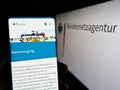 Person holding cellphone with web page of German authority Bundesnetzagentur (BNetzA) on screen with logo.