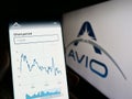 Person holding cellphone with web page of Italian aerospace company Avio SpA on screen in front of logo.