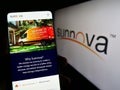 Person holding cellphone with web page of US company Sunnova Energy International Inc. on screen with logo.