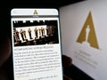 Person holding cellphone with webpage of Academy of Motion Picture Arts and Sciences (AMPAS) on screen with logo.