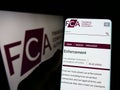 Person holding cellphone with webpage of British Financial Conduct Authority (FCA) on screen in front of logo. Royalty Free Stock Photo