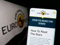 Person holding cellphone with webpage of car safety programme Euro NCAP on screen in front of logo.