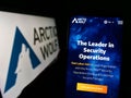 Person holding cellphone with webpage of cybersecurity company Arctic Wolf Networks Inc. on screen with logo.