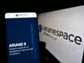 Person holding cellphone with webpage of French aerospace company Arianespace SAS on screen in front of logo. Royalty Free Stock Photo