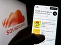 Person holding cellphone with webpage of German music sharing company SoundCloud on screen in front of logo.