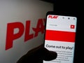 Person holding cellphone with webpage of Icelandic low-cost airline company Fly Play hf. on screen with logo.