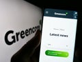 Person holding cellphone with webpage of Irish food company Greencore Group plc on screen in front of logo.