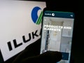 Person holding cellphone webpage logo of Australian mining company Iluka Resources Ltd on screen in front of logo.