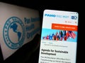 Person holding cellphone with webpage of Pan American Health Organization (PAHO) on screen in front of logo. Royalty Free Stock Photo