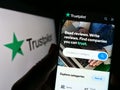 Person holding cellphone with webpage of review platform company Trustpilot Group plc on screen with logo.
