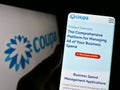 Person holding cellphone with webpage of spend management company Coupa Software Inc. on screen with logo.