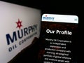 Person holding cellphone with webpage of US exploration company Murphy Oil Corporation on screen with logo.