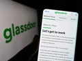 Person holding cellphone with webpage of US job review company Glassdoor Inc. on screen in front of logo.