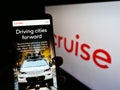 Person holding cellphone with website of American self-driving car company Cruise LLC on screen in front of logo.