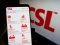 Person holding cellphone with website of Australian pharmaceuticals company CSL Limited on screen in front of logo.