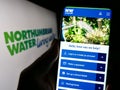 Person holding cellphone with website of British company Northumbrian Water Limited on screen in front of logo. Royalty Free Stock Photo