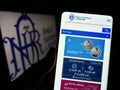 Person holding cellphone with website of central bank Banca Nationala a Romaniei (BNR) on screen with logo.