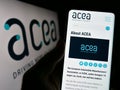 Person holding cellphone with website of European Automobile Manufacturers Association (ACEA) on screen.