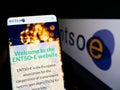 Person holding cellphone with website of European energy association ENTSO-E on screen in front of logo.