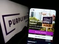 Person holding cellphone with website of real estate company Purplebricks Group plc on screen in front of logo. Royalty Free Stock Photo