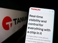 Person holding cellphone with website of US cybersecurity company Tanium Inc. on screen in front of logo.