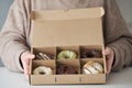 Person holding a choice of various delicious crafted donuts from a takeaway box.